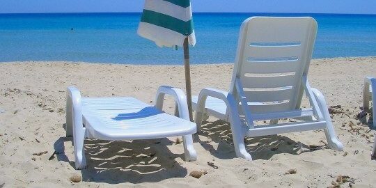 Leere Liegestühle am Strand mit Sonnenschirm. Social Media Marketing im Sommer.